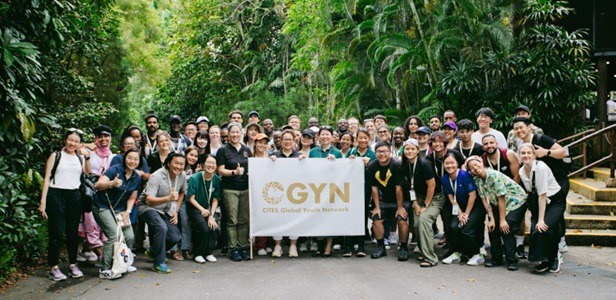 A photograph of a large group of people behind a banner that reads CGYN